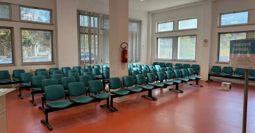 Sala d'attesa dell'Ematologia dell'Ospedale Businco con sedute verdi lavabili e cartello Accettazione Ematologia