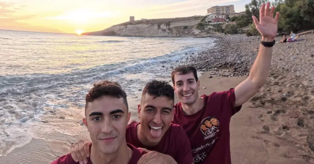 Alessio, Fabio e Gabriele di “Pedalando per bene” con le magliette dell’iniziativa su una spiaggia al tramonto