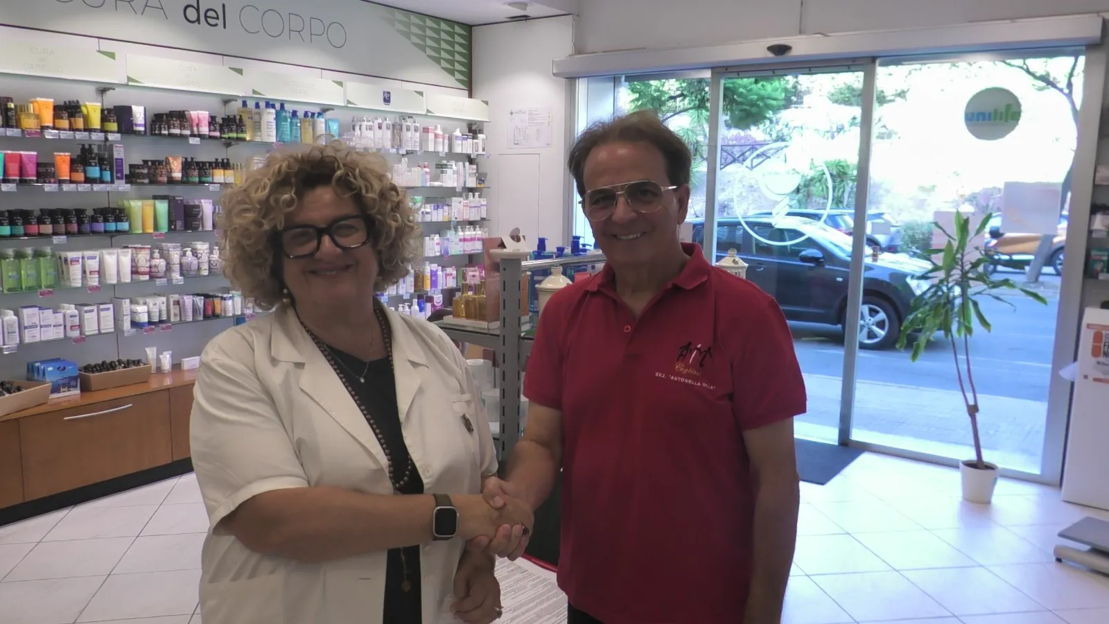 Stretta di mano tra il presidente di AIL Cagliari Renzo Pili e la presidente di Federfarma Cagliari Maria Pia Orrù nella Farmacia Orrù di Cagliari.